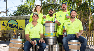 Five people posing with beer kegs in front of the Islamorada Beer Company sign